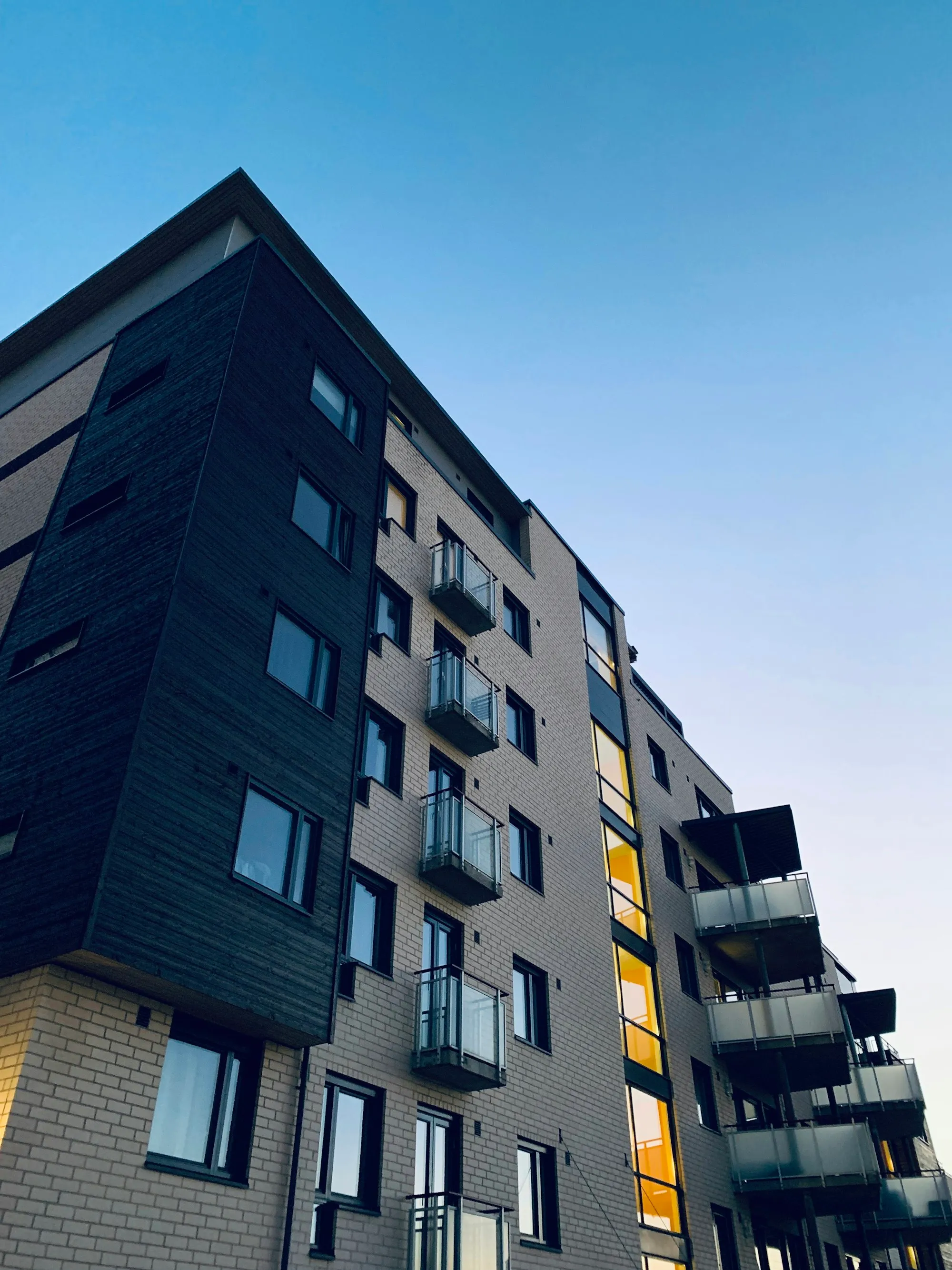 A modern mid-rise apartment building with windows stacked across its facade.